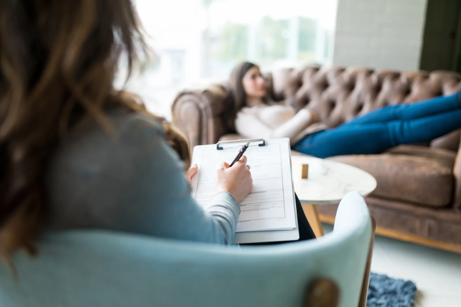 A clinician taking notes while a client talks during an evaluation