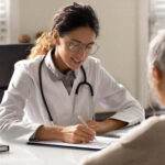 Female doctor write prescription to elderly patient