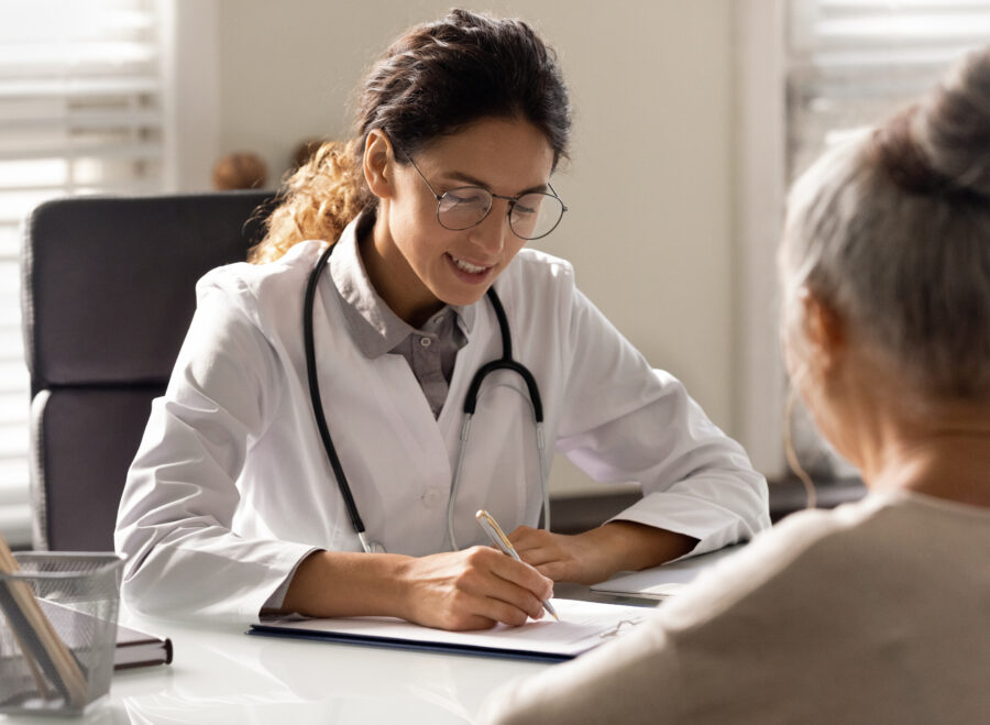 Female doctor write prescription to elderly patient